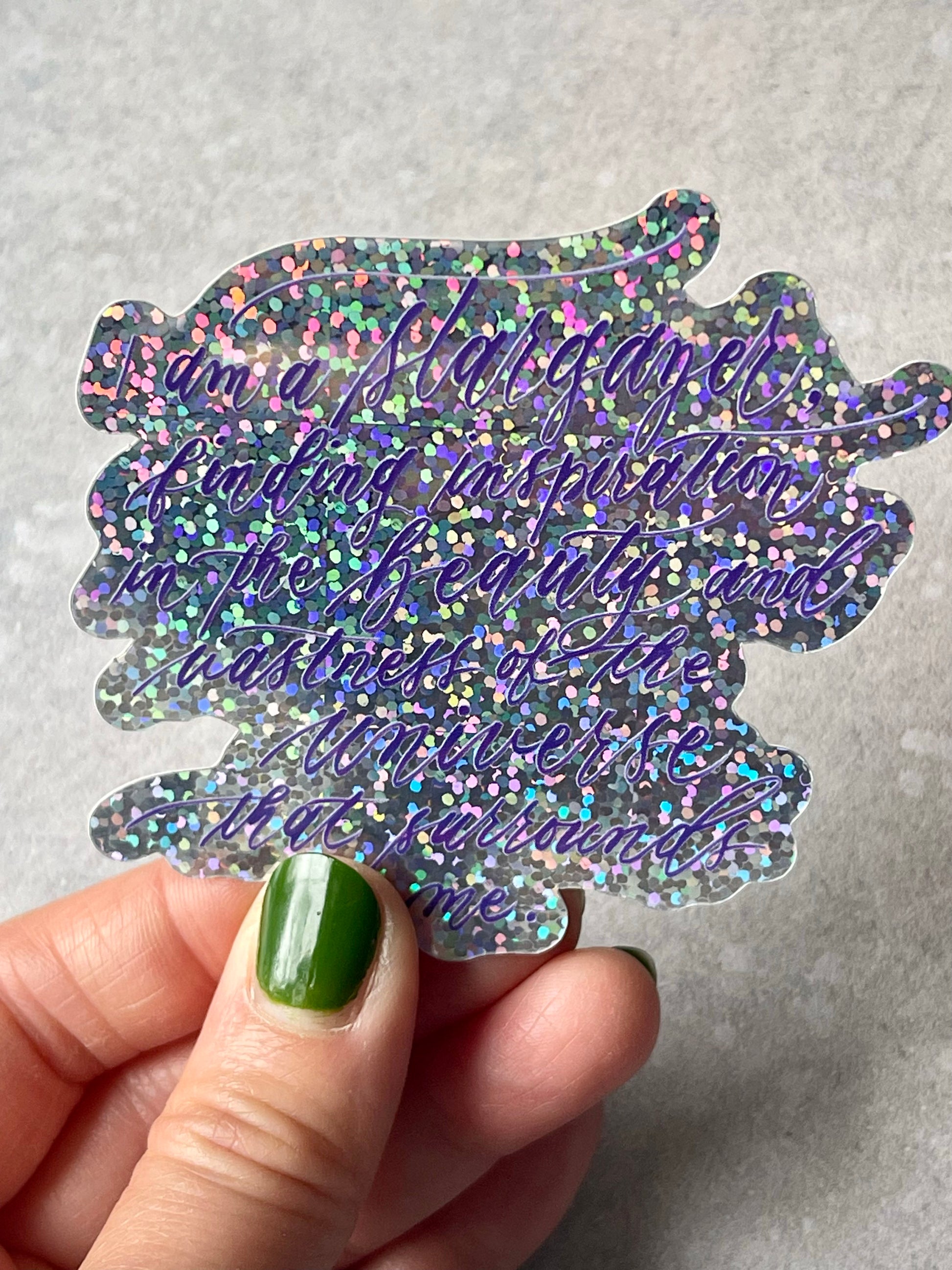 I am a stargazer finding inspiration in the beauty and vastness of the universe that surrounds me script calligraphy glitter sticker in shiny view catching light with shiny ombre purple and pink tones