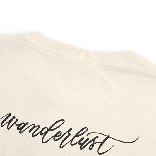 Wanderlust script printed on back of ivory t-shirt flat lay sideways.