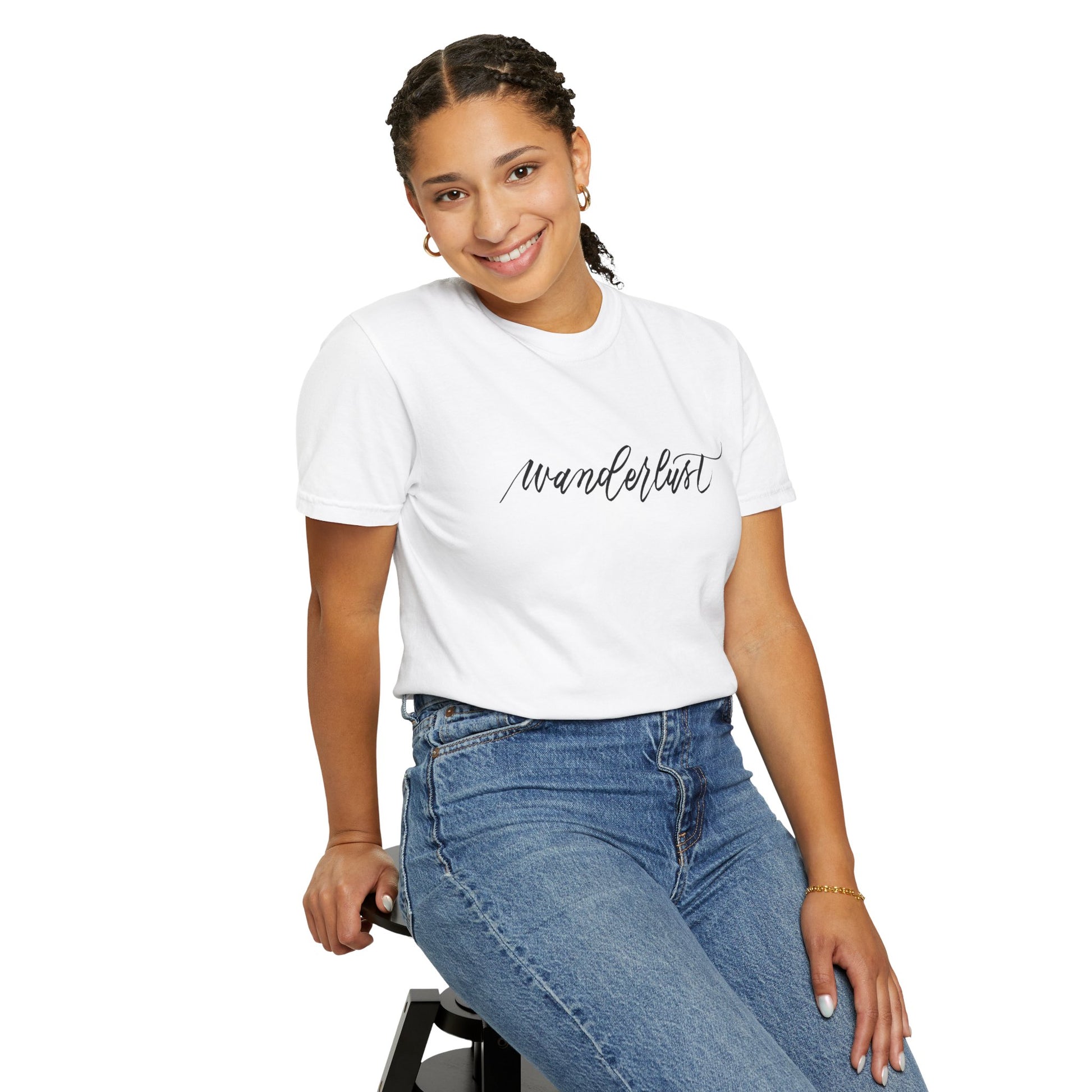 Smiling woman sitting down wearing a white t-shirt and jeans. White t-shirt reads "wanderlust" handwritten in beautiful calligraphy.