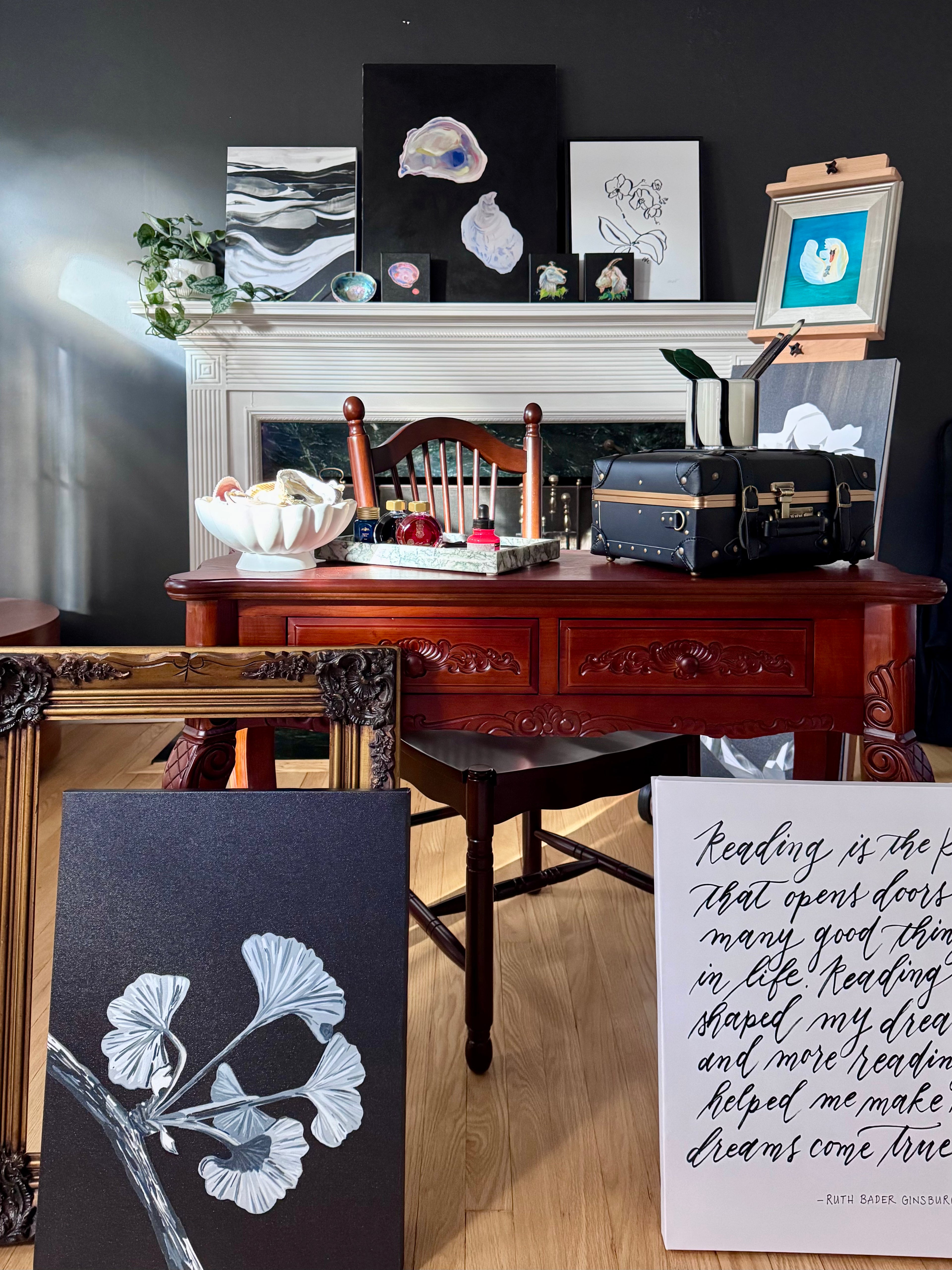 Decorative room artist studio with a wooden desk, framed artwork, and a dark wall.